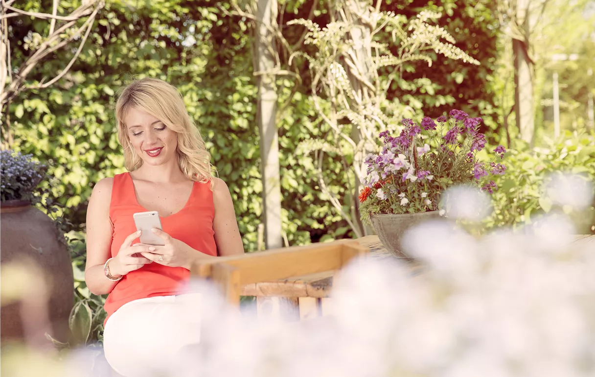 Frau im Garten mit Smartphone