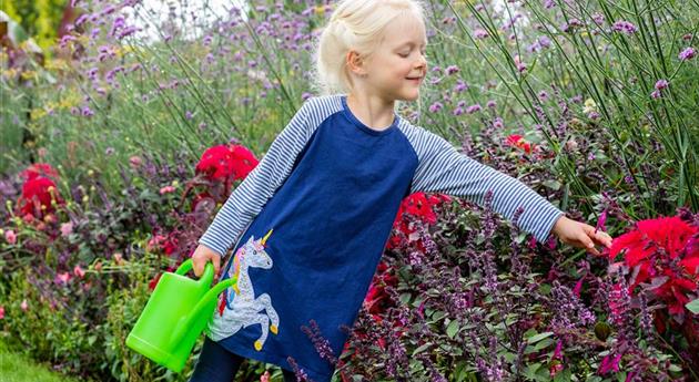 Kind im Garten - Blumen gießen