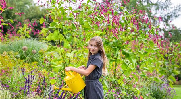 Kind im Garten - Blumen gießen