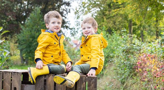 Apfelernte- Kinder sitzen auf Apfelkisten