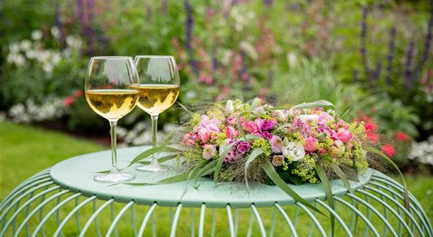 Blumenkranz und Weinschorle auf Gartentisch