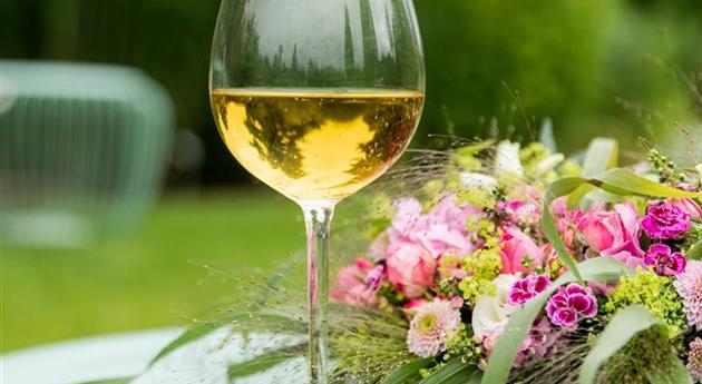 Blumenkranz und Weinschorle auf Gartentisch